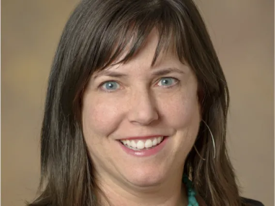 Julie, smiling white woman with brown hair and wearing a turquoise necklace