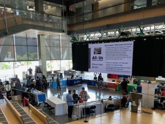 A wide-angle photo of the event, showing groups of people gathered around information tables.