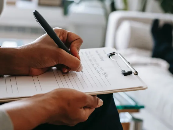 Image of a psychologist writing on clipboard during session