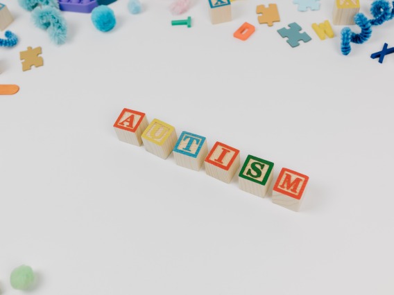 A Word Autism Spelled With Letter Blocks on a White Surface