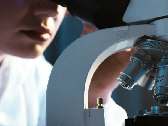 A healthcare worker looking through the microscope