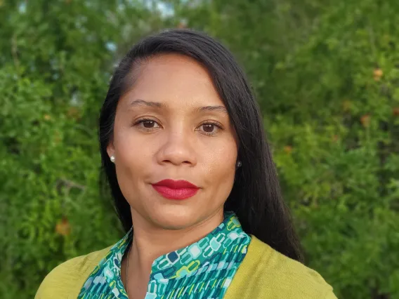 Jacy, a smiling Black-Filipina woman with dark long hair in green top and yellow cardigan