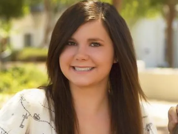 Woman with dark long hair in white top smiling