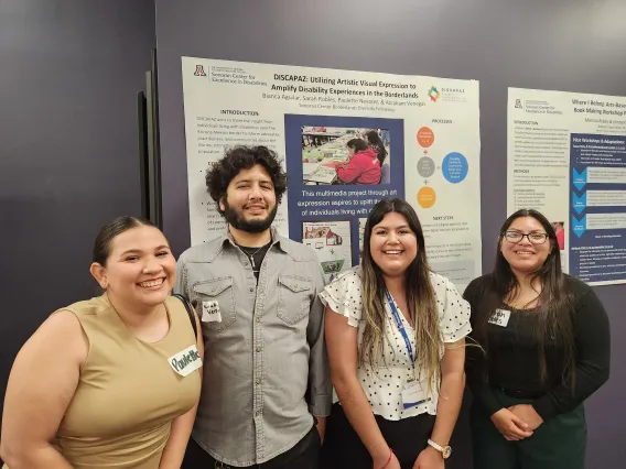 Four people standing in front of a large research poster