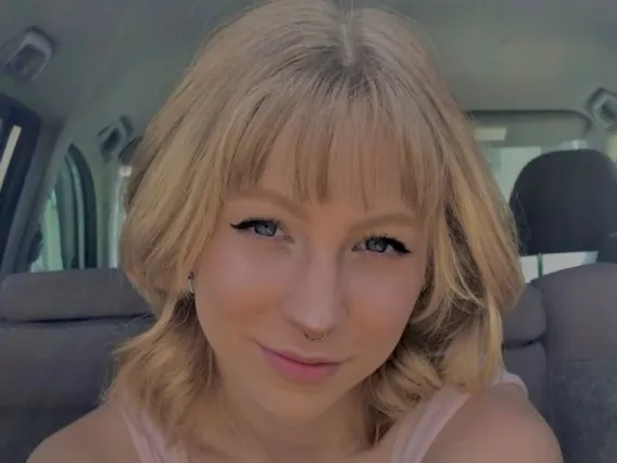 Amber Chase, a young woman with blonde hair, sitting in a car with a slight smile