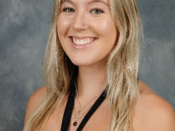Kiley McNeil, a young person with long blonde hair, wearing a black top, in front of a grey background