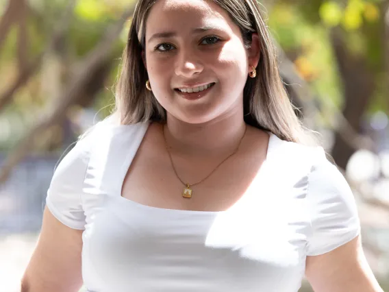 Photo of woman wearing a white blouse with brunette hair and is smiling at the camera