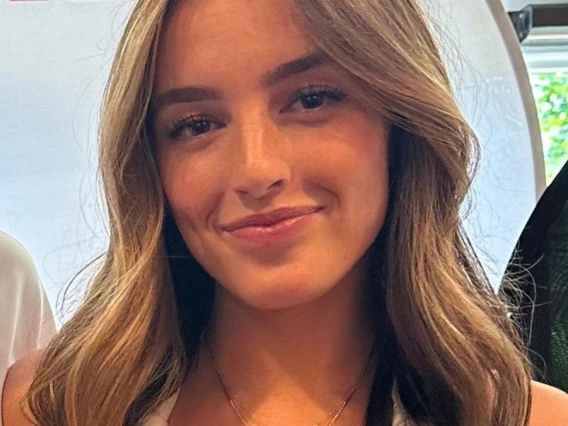 Picture of woman with brunette hair past her shoulders, wearing white blouse and is smiling at the camera