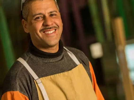 A picture of a man with glasses on his head, and work attire on that is tan and orange.