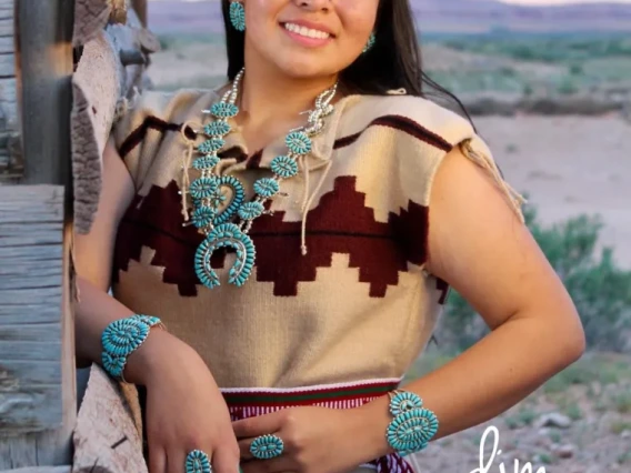 Alanna Begay, a young person with long brown hair, standing outside, wearing a brown dress and smiling