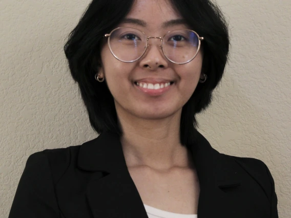 Nadine Chau, a young person with shoulder length black hair and glasses, wearing a white top and black blazer, smiling