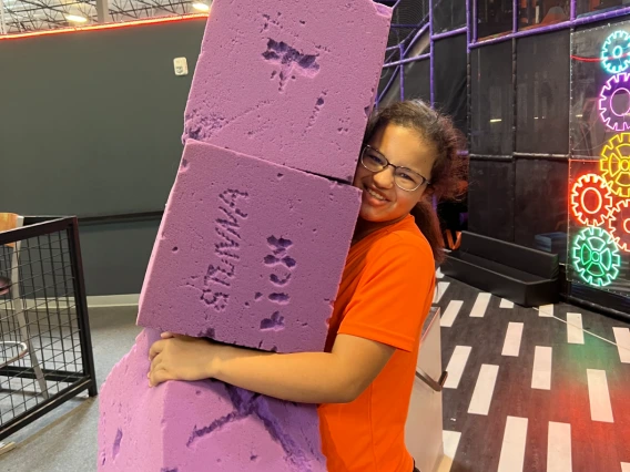 Person holding purple foam blocks.