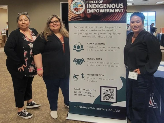 Left to right: Agnes Attakai, Rosa Rojas-Franco, and Mỹ Lê Sandaine stand next to a banner for the Circle of Indigenous Empowerment