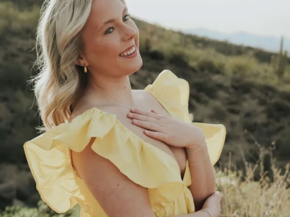 Lauren Elizabeth Mitchell, wearing a yellow dress and standing in a field, smiling