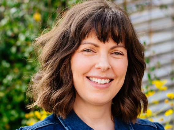 woman with chin length wavy hair and bangs, she is smiling at the camera
