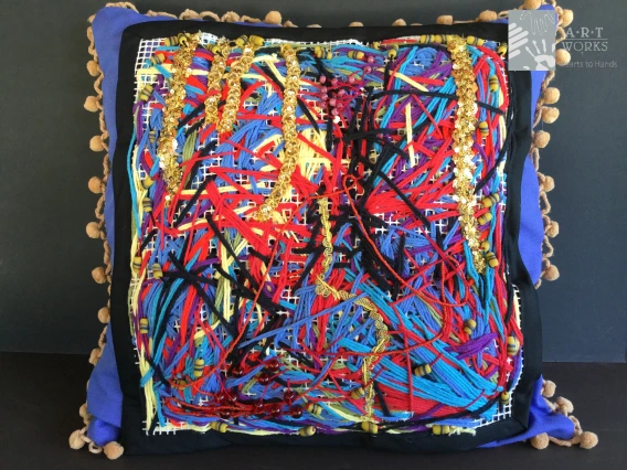 pillow with different yarn and fabrics sewed onto the front