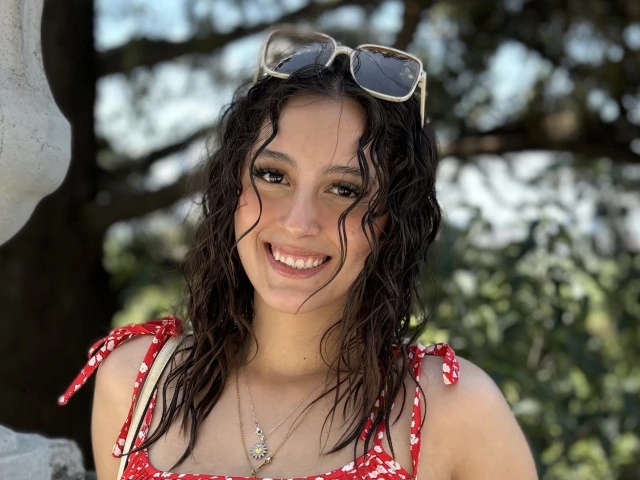 young woman with curly black hair and is smiling at the camera