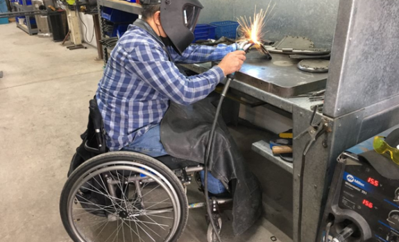 Man on a wheelchair welding
