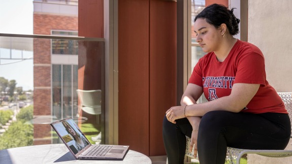 A woman wearing red UA top sitting next to a laptop