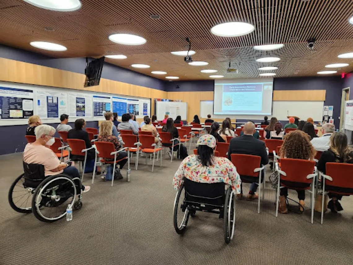 The symposium audience watches Yolanda Reyes' presentation, "Early Intervention Services: Importance and Relevance"