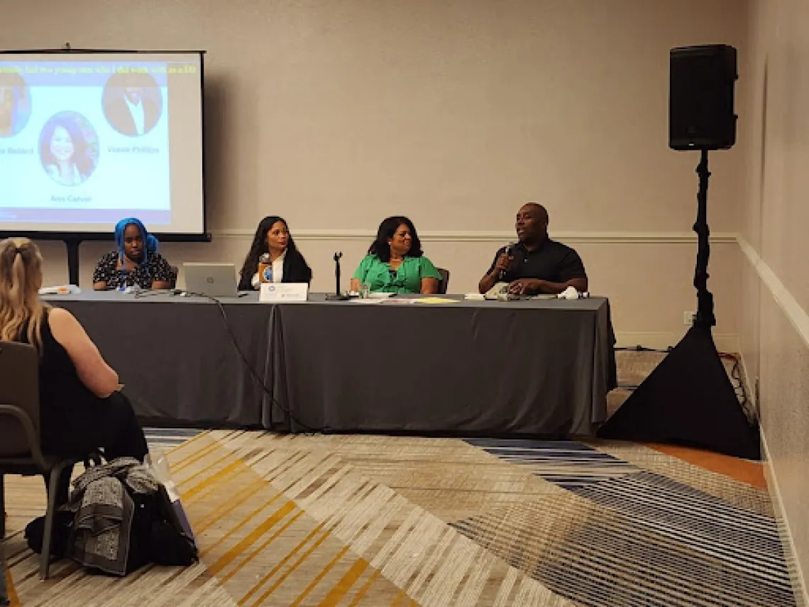 Four people sitting as panelists at a long table