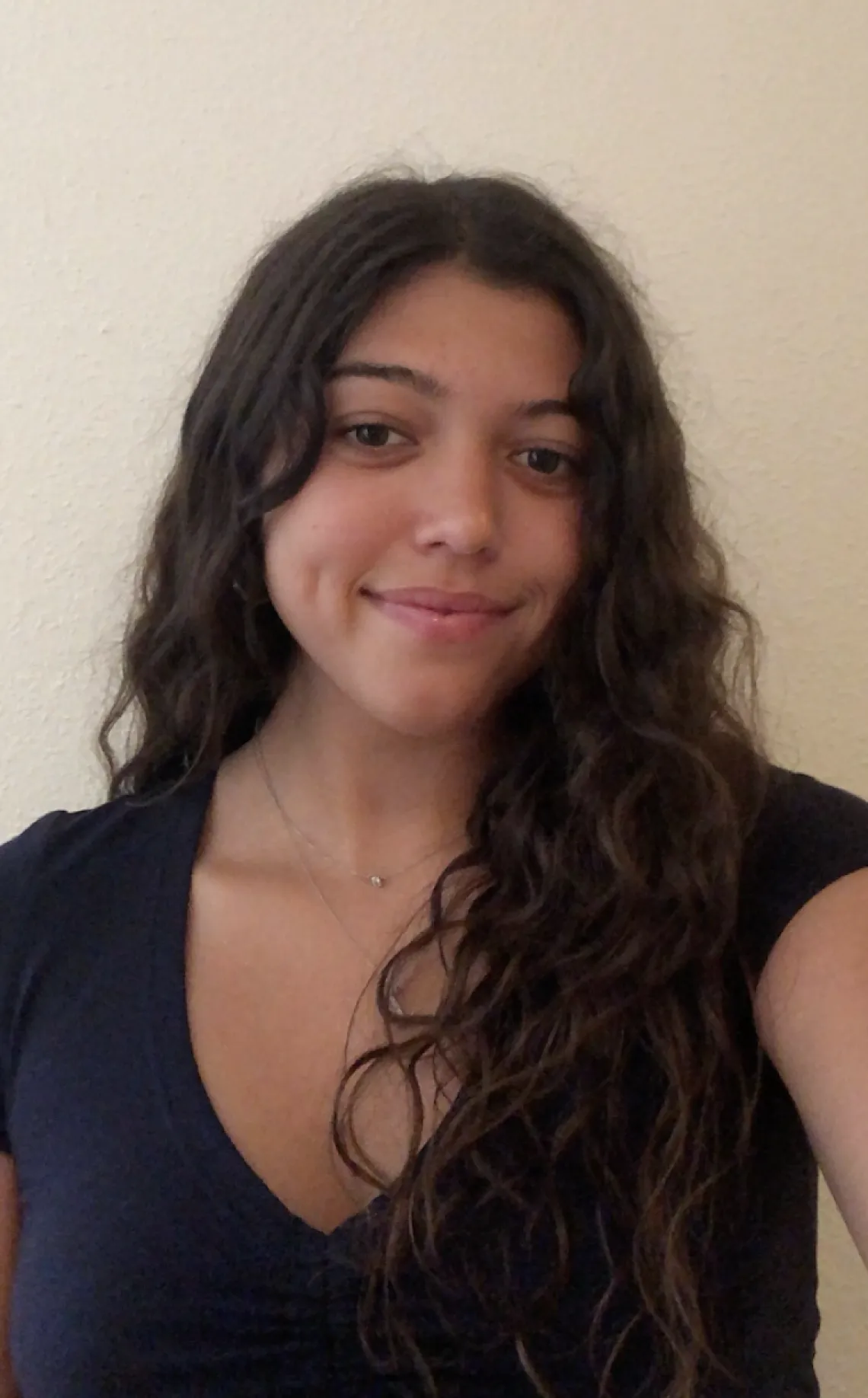 Bi-racial girl with long dark curly hair wearing a black v-neck t-shirt