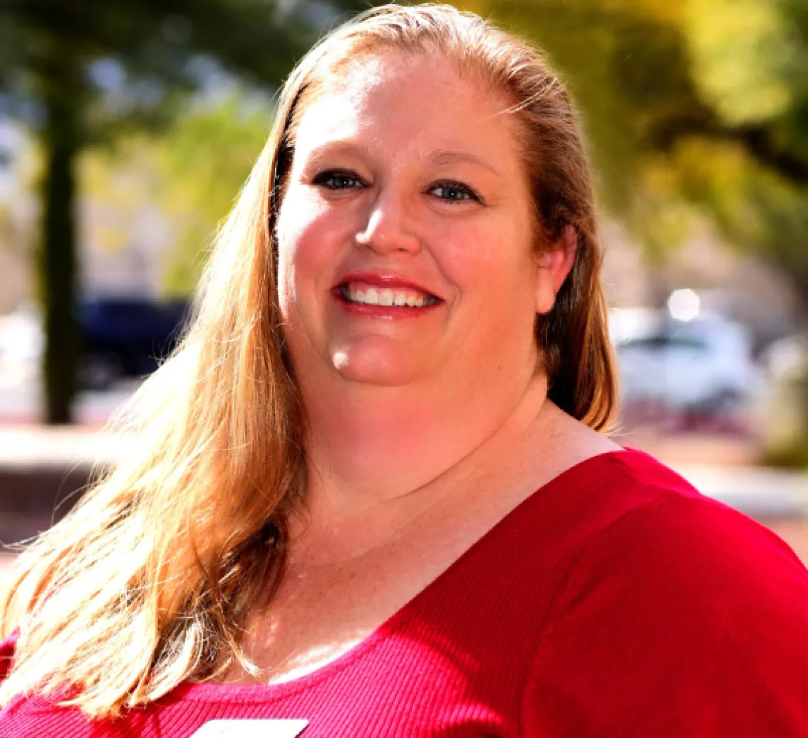 Danielle Hallahan, a white woman, standing outside wearing a red shirt