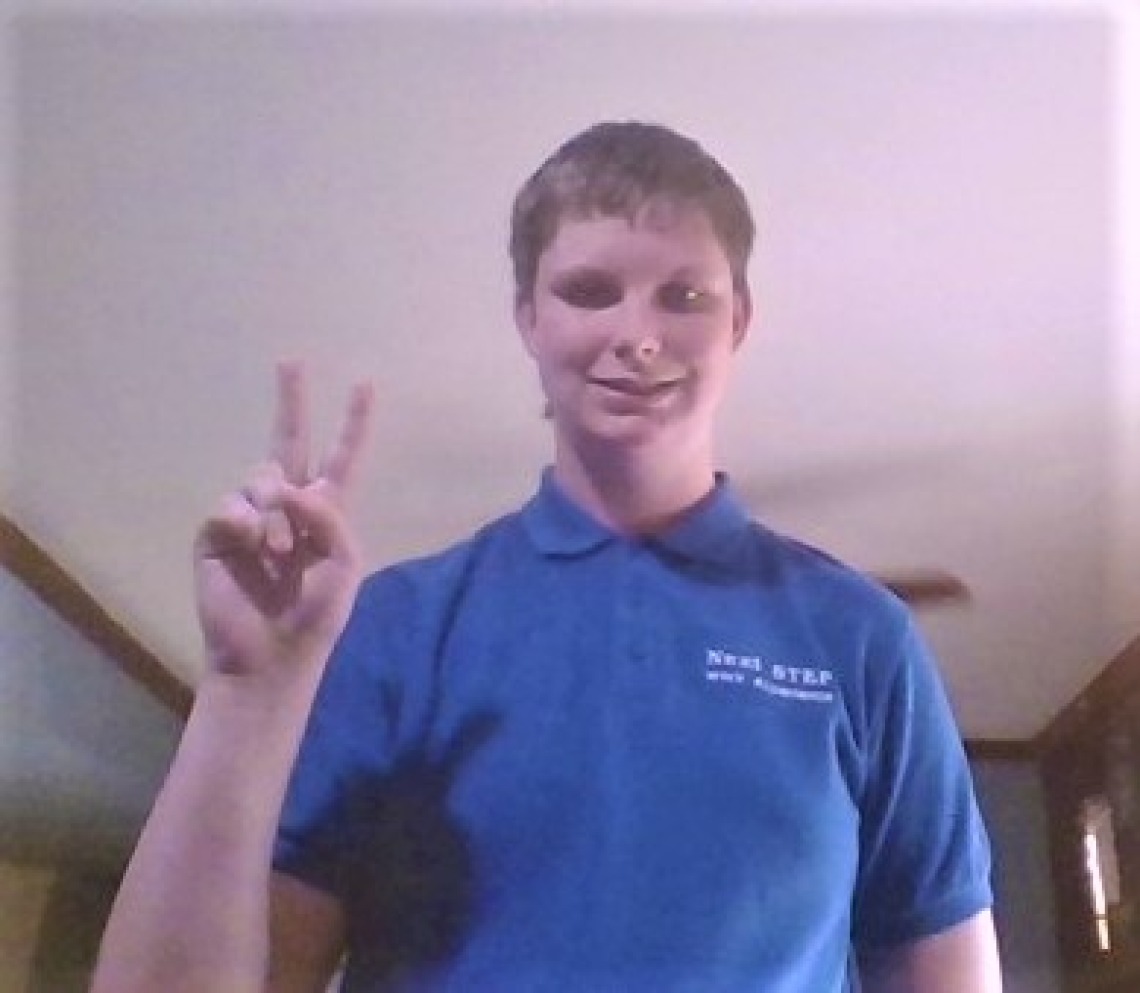 Lexi Dibbern, a white teenager with short hair in a blue polo shirt doing the "peace" sign