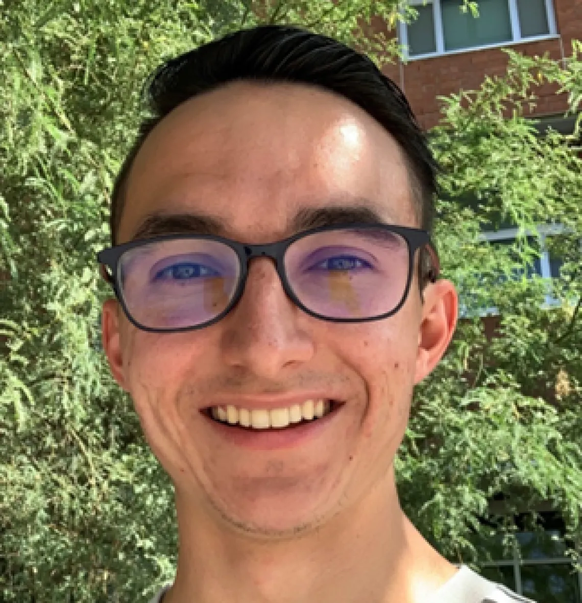 Nick Marcell, Sonoran Center trainee, smiling in front of some trees