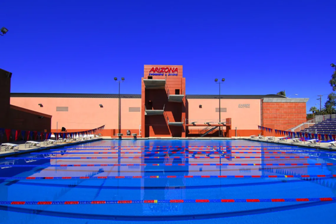 an outdoor swimming pool in front of a building with UArizona branding