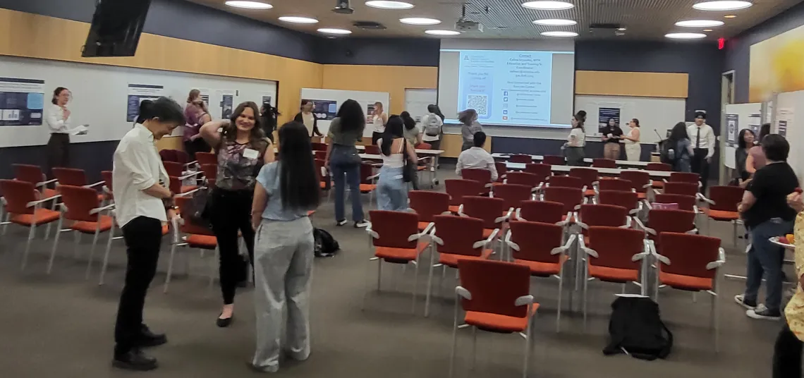 trainees show their posters and discuss their findings at the symposium