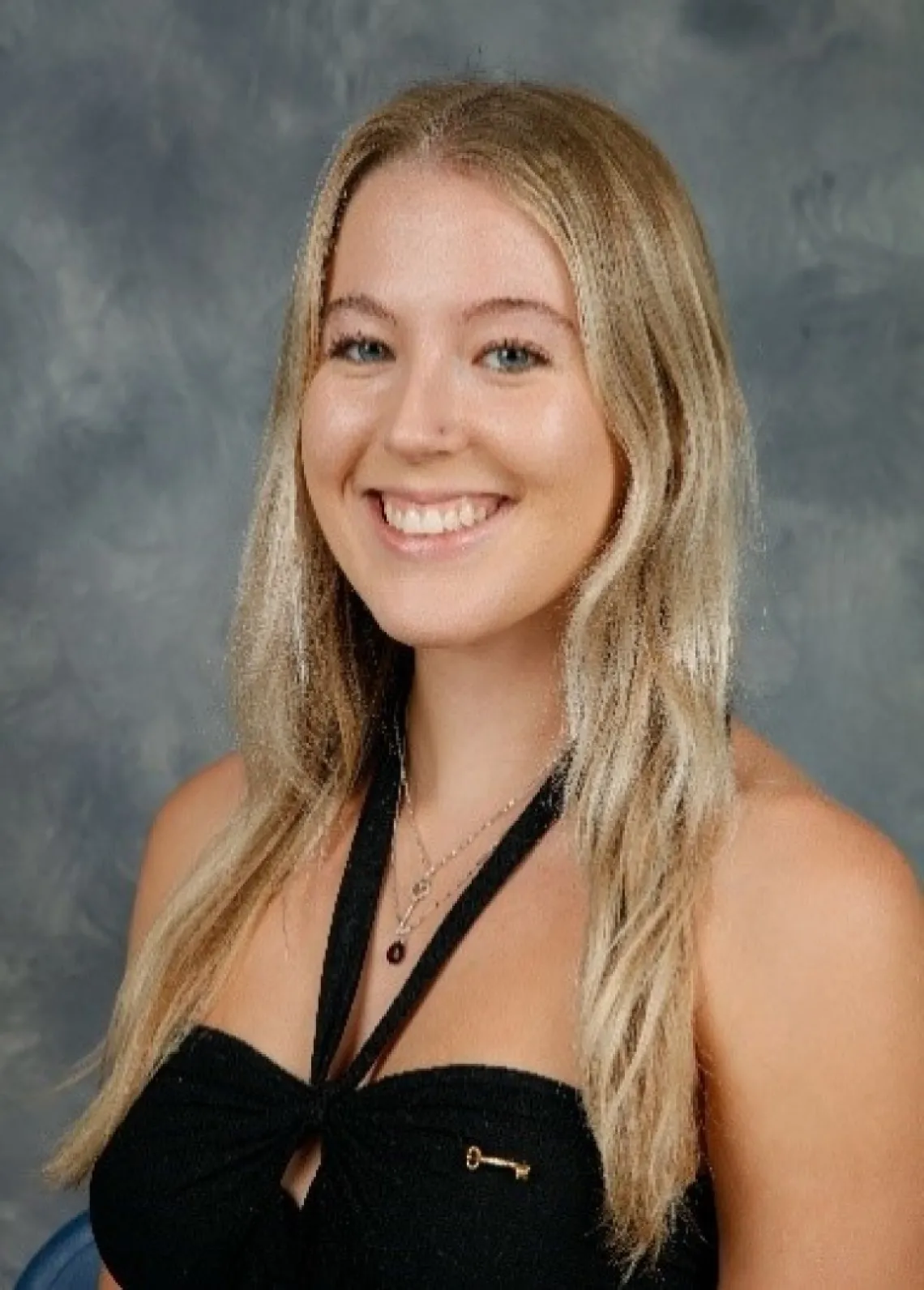 Kiley McNeil, a young person with long blonde hair, wearing a black top, in front of a grey background