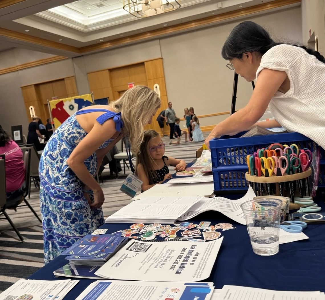 Dr. Yumi Shirai shows a young girl and her mother how to create a scrapbook page