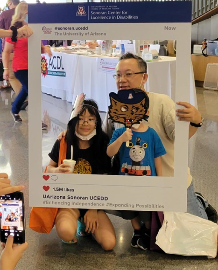 a man, girl, and boy with Wilbur Wildcat mask posing for a photo at the Backpacks and Boosters event. A father holds up a frame which mimics a Sonoran Center Facebook post. The girl and boy are also in the frame. A person with a phone takes a photograph of the three.  News Open News configuration options Finding Their Way: Native Youth with Disabilities Share Their Voice Read more Open configuration options Anya Finding Their way headshot Sonoran Center Affiliated Faculty Named 2022-2023 UA