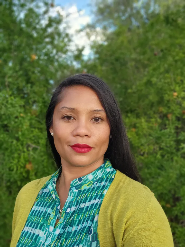 Jacy, a dark long hair woman in green top and yellow cardigan smiling