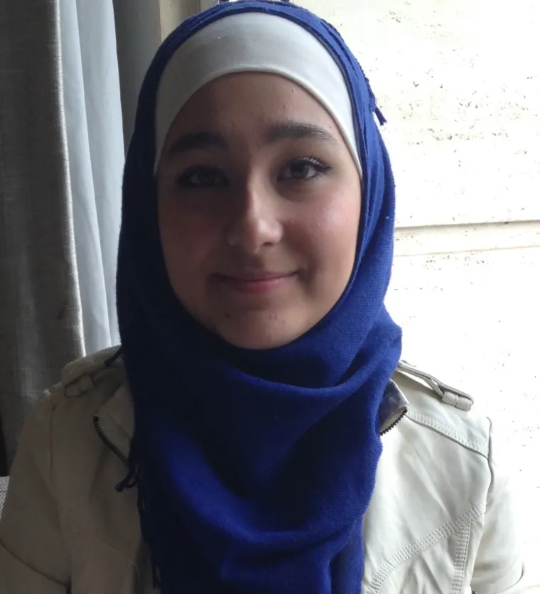 Mumina, a woman in blue hijab smiling