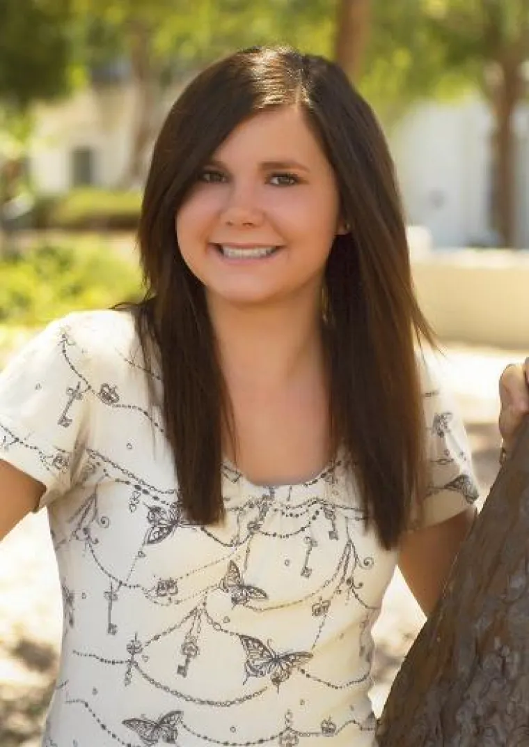 Woman with dark long hair in white top smiling