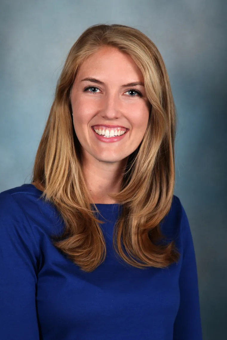 A Blonde woman with blue top smiling 