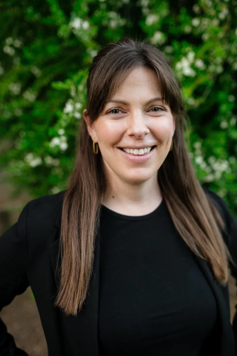Woman with long light brown hair wearing a black top