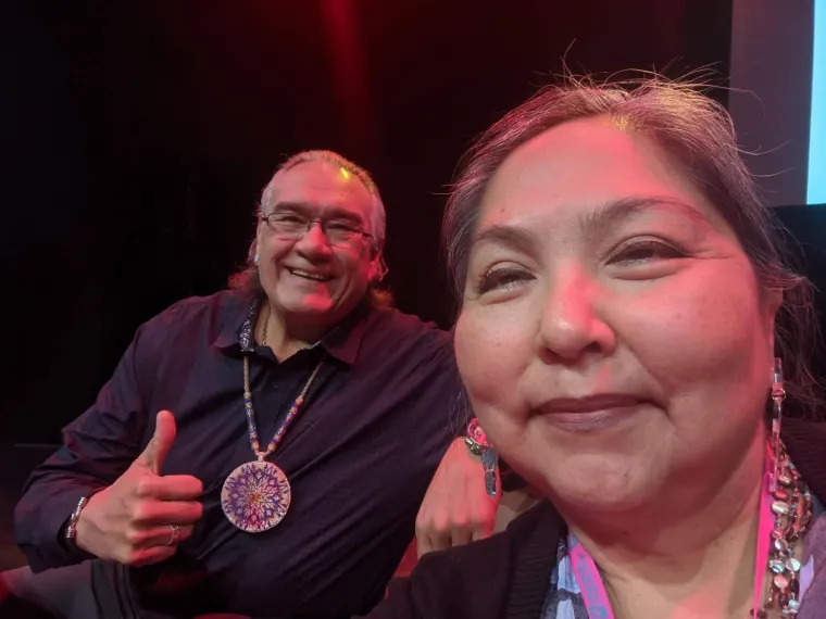 Jim E. Warne (left) and Agnes Attakai (right) at the CANAR conference. Both sitting and smiling, facing the camera.