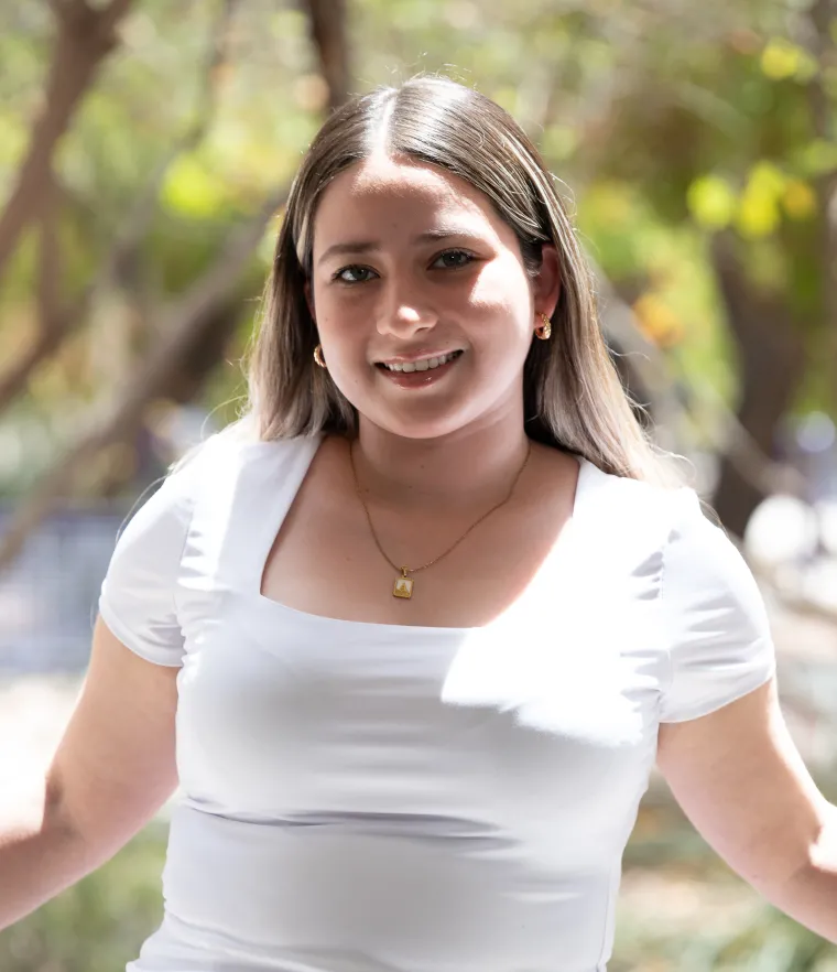 Photo of woman wearing a white blouse with brunette hair and is smiling at the camera