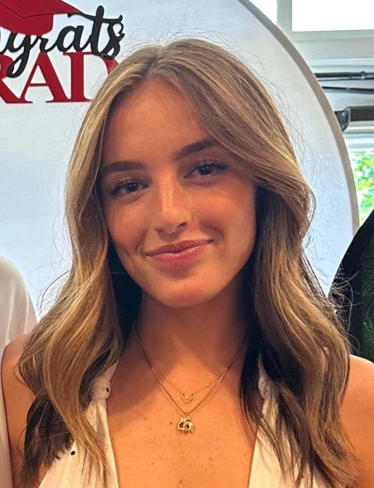 Picture of woman with brunette hair past her shoulders, wearing white blouse and is smiling at the camera