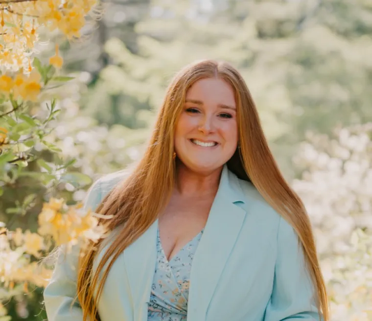 Portrait of Makenna Thuringer, a white woman with long straight red hair, wearing a powder blue blazer.