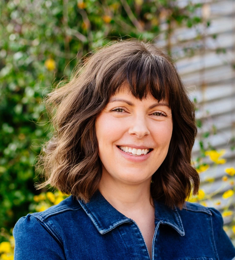 woman with chin length wavy hair and bangs, she is smiling at the camera