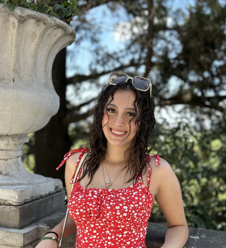 young woman with curly black hair and is smiling at the camera