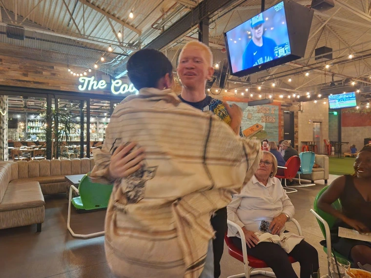 Kelvin embraces Jacy while wrapping the Tanzania cloth around her shoulders