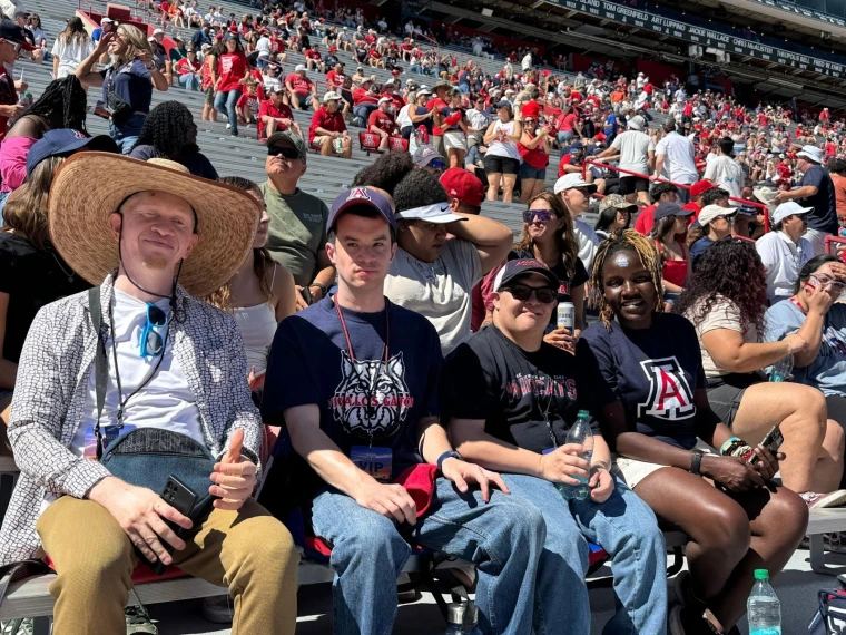 Kelvin, Gabe, and Mai in the stands at a U of A football game. 