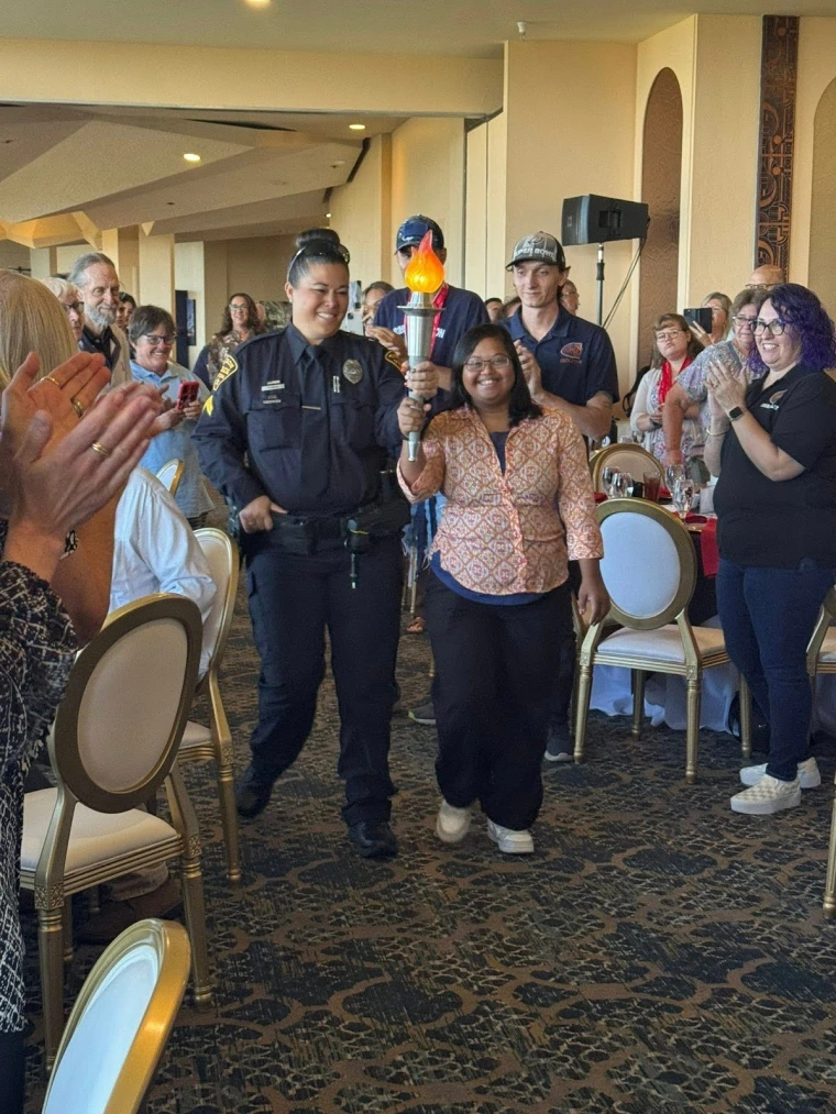 Pavleena Madhivanan and a TPD representative walk with the Torch between the breakfast tables