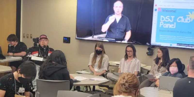 Group of people sitting in the front of a classroom with a display screen saying "DSJ Club Panel" behind them