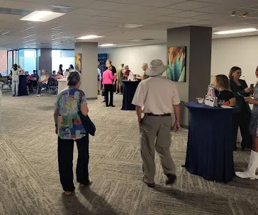 An older couple walks into the gallery for the ArtWorks opening. In the background, other attendees converse and enjoy refreshments.